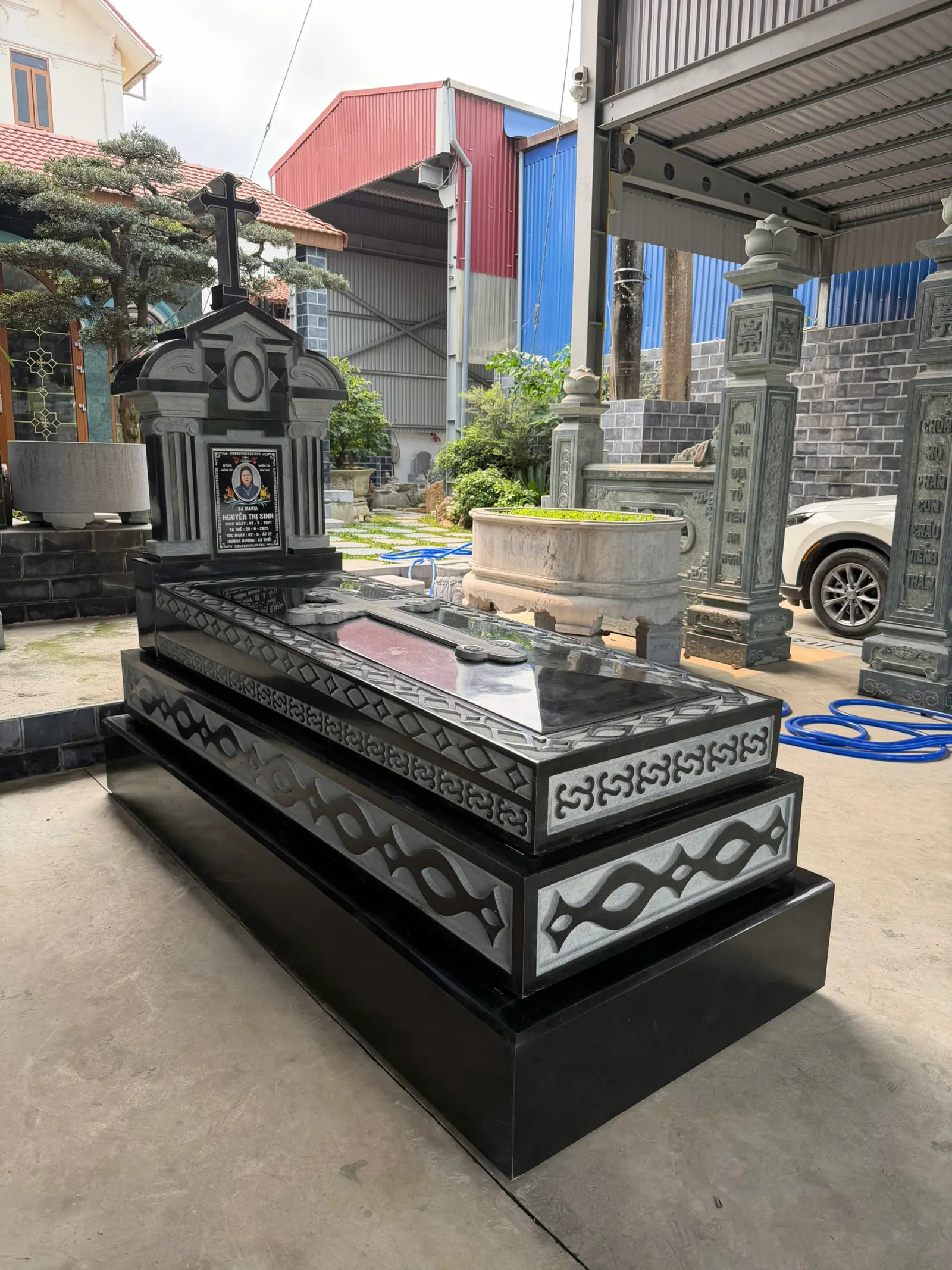 Mộ Đá Granite Đen Công Giáo — Mẫu Đẹp, Bền Vĩnh Cửu 2026 4 Hoa văn đặc trưng Công giáo (nho — lúa mì — thiên thần) khắc tay trên mặt bia granite đen bóng gương