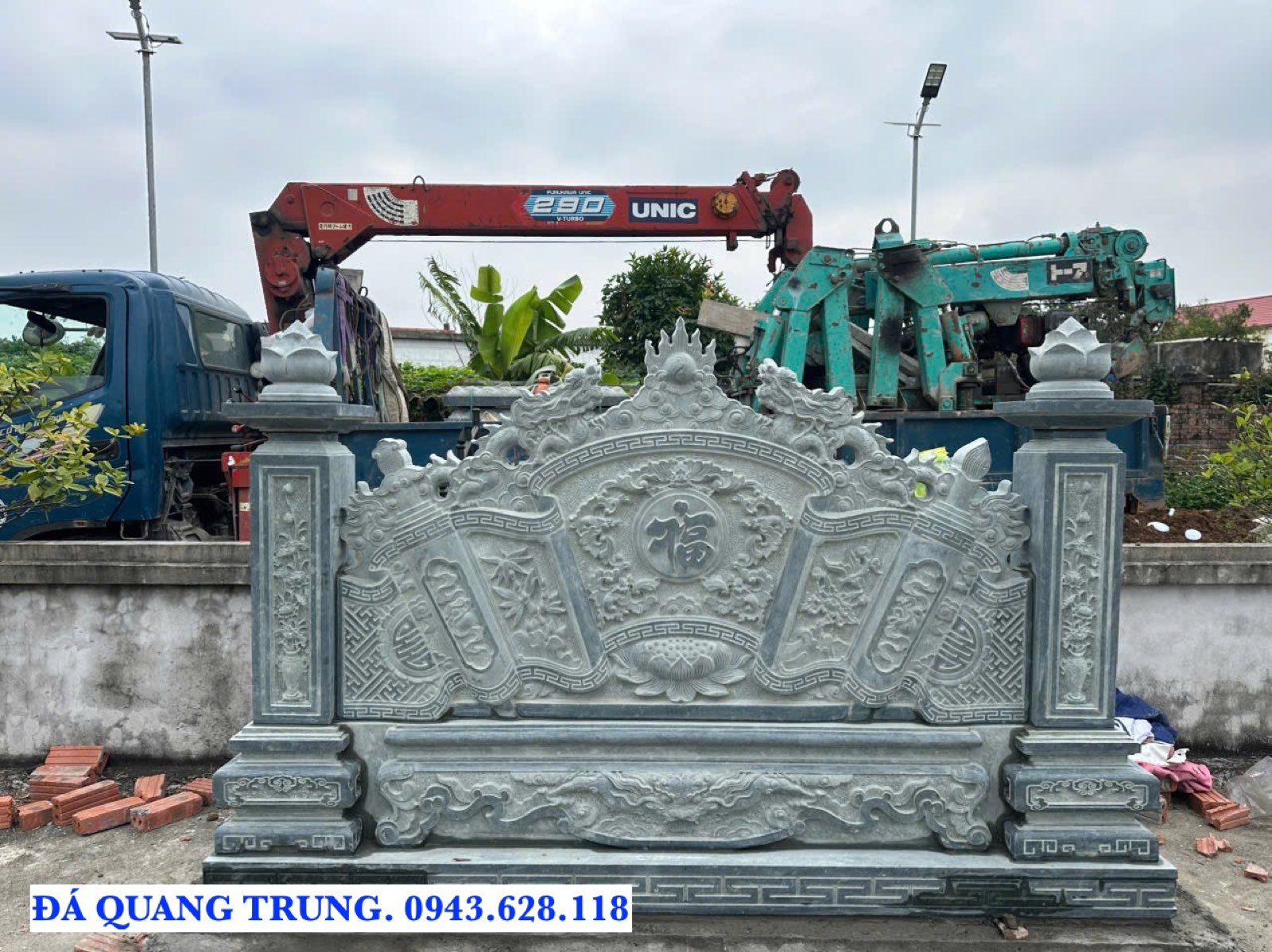 Cuốn thư đá hình cuộn thư vừa dựng tại công trình, phía sau là xe cẩu dùng để nâng đá