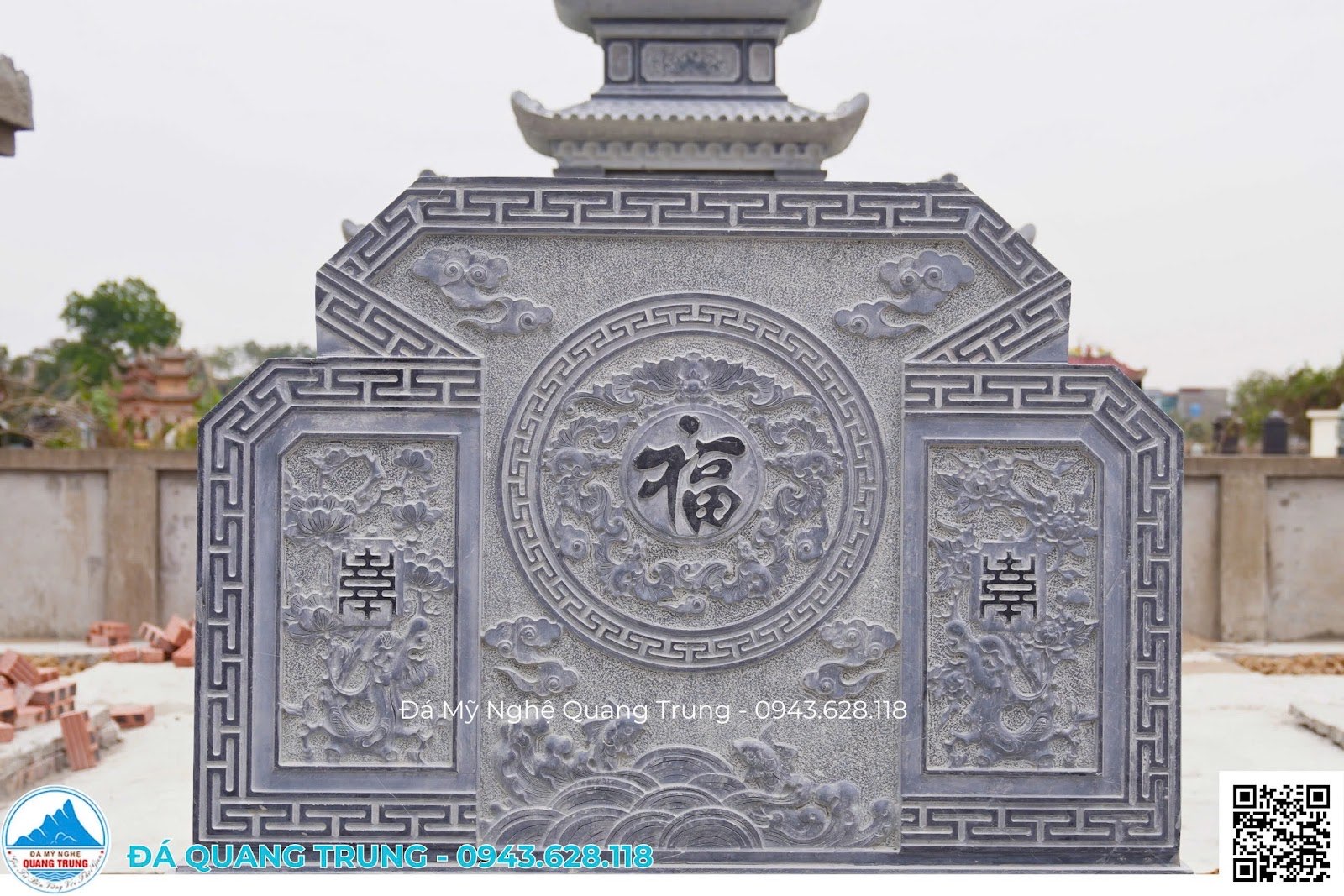 Cận cảnh cuốn thư đá với chữ Phúc trong vòng tròn hồi văn, hai ô bên chạm hoa lá và chữ triện